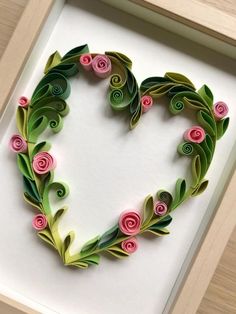 a paper heart with pink flowers and green leaves in the shape of a flower arrangement