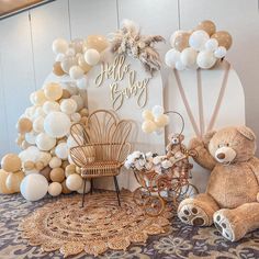 a teddy bear sitting in front of a balloon arch