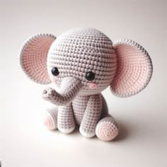 a small crocheted elephant sitting on top of a white table next to a wall