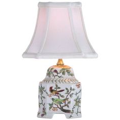 a lamp with a bird on it and a white shade over the top of it