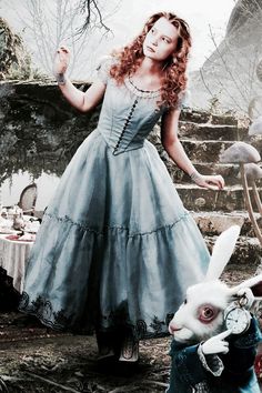 a woman in a blue dress standing next to a rabbit