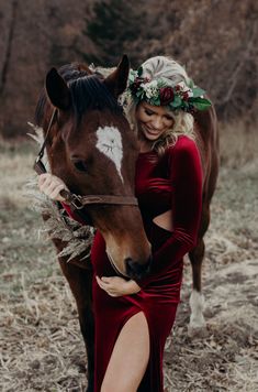 a woman standing next to a horse wearing a red dress and flower headpieces