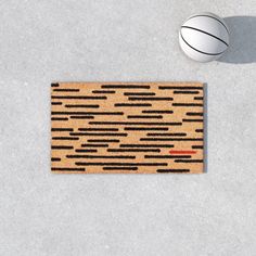 a basketball is sitting on the floor next to a door mat that has an abstract design