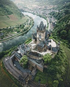 an aerial view of a castle in the middle of a river and town below it