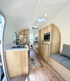 a kitchen and living room inside an airstream with wood flooring on the walls