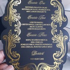 a person holding up a black and gold wedding menu