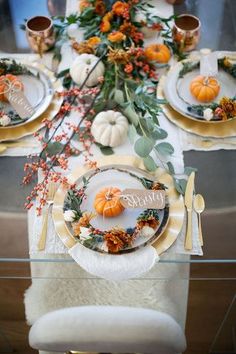 the table is set with plates and place settings for thanksgiving dinner, including pumpkins