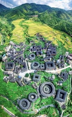 an aerial view of a village surrounded by green hills and rice fields in the background