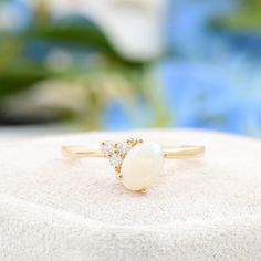 a close up of a ring on top of a white surface with flowers in the background