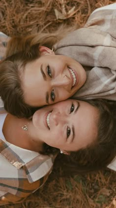 two women are laying on the ground smiling at the camera and posing for a photo