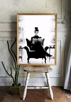 a black and white photo of a woman sitting in a chair with a book on her lap