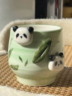 two panda bears sitting in a ceramic cup