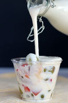 a person pouring milk into a bowl filled with food