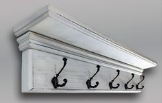 an old white coat rack with black hooks on it's sides and two coats hanging from the top