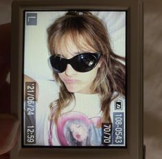 a person holding up a cell phone with an image of a woman wearing sunglasses on it