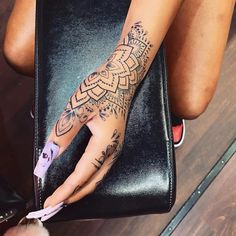 a woman's hand with tattoos on it sitting on top of a black chair