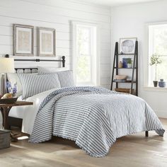 a bed with blue and white striped comforter in a bedroom next to a window