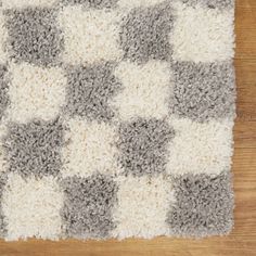 a gray and white checkered rug on top of a wooden floor