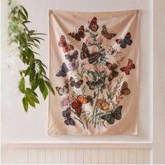 a wall hanging with butterflies on it next to a potted plant in front of a window