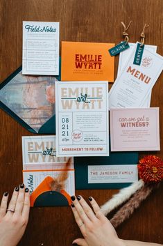 a woman's hands on the table with various wedding stationery