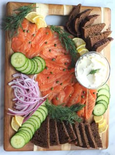 salmon, cucumbers, onions, dill and bread on a cutting board