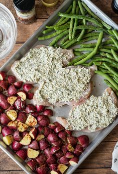 a tray filled with meat, potatoes and green beans on top of a wooden table