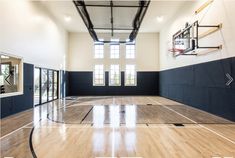 an indoor basketball court with hard wood flooring and glass doors leading to the outside