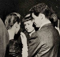 an old black and white photo of two people standing next to each other, talking