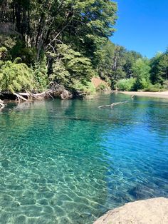 the clear blue water is surrounded by trees and rocks in the middle of the river