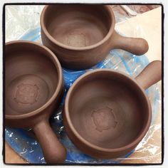 three brown ceramic cups sitting on top of a plastic bag