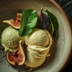 three scoops of ice cream with figs and leaves in a bowl on a table