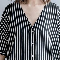 Feel comfortable while keeping it casual in our Black and White Striped Blouse. This blouse has an artsy style that is made to be your new go-to. Its flowy cotton material keeps it airy and light making it wearable even in the hottest months while its long sleeves and length makes it great for colder days. The monochromatic pattern and structured button-up style add a professional look that balances its easy-going fit. Wear this shirt day or night wherever you please, this versatile blouse will Striped Cotton V-neck Blouse, Flowy Cotton V-neck Blouse, Effortless V-neck Blouse For Day Out, Flowy V-neck Casual Blouse, Striped V-neck Shirt For Summer, Oversized V-neck Shirt For Summer, Relaxed V-neck Blouse For Day Out, Summer Chic Striped Shirt, Striped Blouse For Summer Daywear