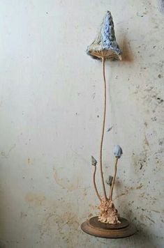 a small blue and white flower on a wooden stand in front of a dirty wall