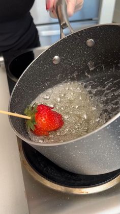 a strawberry being cooked in a wok on top of a stove with boiling water