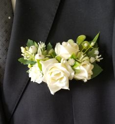 a boutonniere with white flowers and greenery on it's lapel