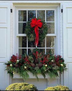 a christmas wreath on the window sill with evergreens and red berries in it