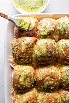 a pan filled with rolls covered in cheese and sauce