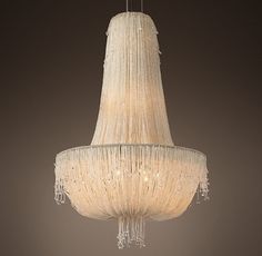 a white chandelier hanging from a ceiling in a room with dark walls and flooring