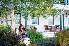 a woman sitting on a bench in front of a house