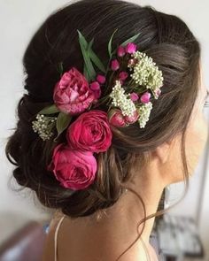 a woman with flowers in her hair is wearing a flowered updo hairstyle