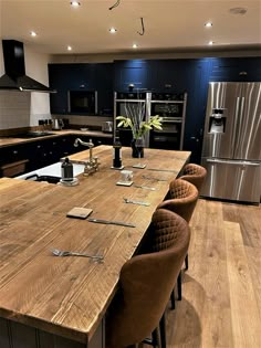 a kitchen with an island made out of wooden planks and metal appliances in the background