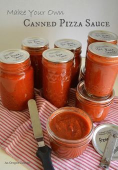 several jars of canned pizza sauce sitting on a table with a knife and spoon next to them