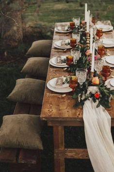 a long wooden table topped with plates and candles