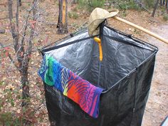 a black trash can with a hat on top and clothes hanging out to dry in the rain