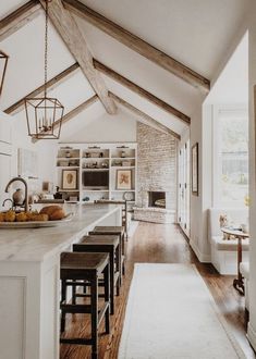 an open kitchen and dining room with white walls, wood beams and exposed ceilinging