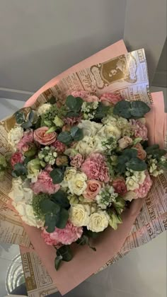 a bouquet of pink and white flowers on top of a piece of paper with green leaves