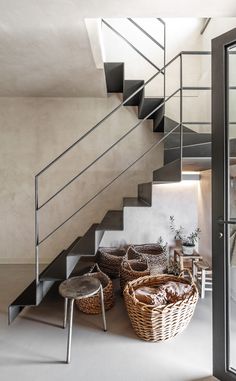 the stairs in this house are made of concrete and black iron, with wicker baskets under them