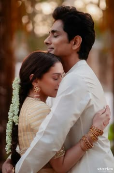 a man and woman embracing each other in front of trees