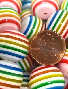 a penny sitting on top of some colorful striped balls with one penny in the middle