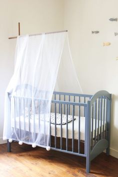 a baby crib in a room with fish on the wall and curtains over it